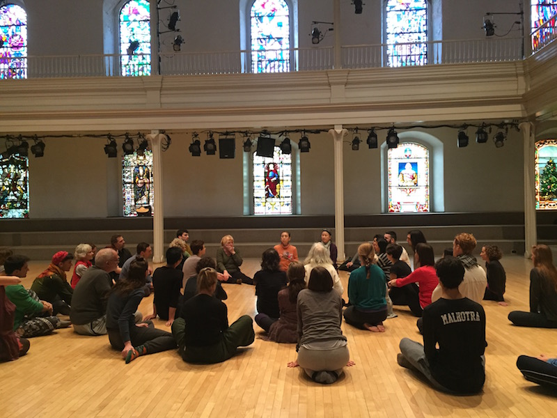 Eiko leads a discussion during her workshop. Participants sit on the floor around her in the space.